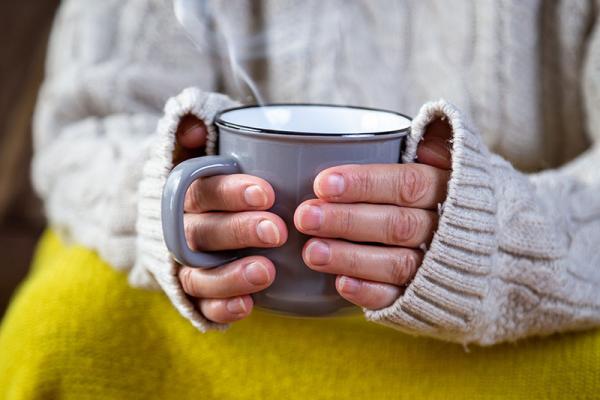 a steaming mug of tea being held in a lady's hands