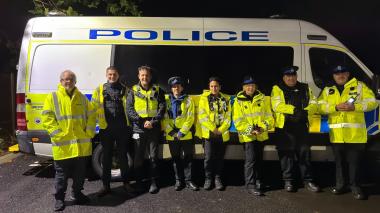 Police officer and community safety officers in front of a police van